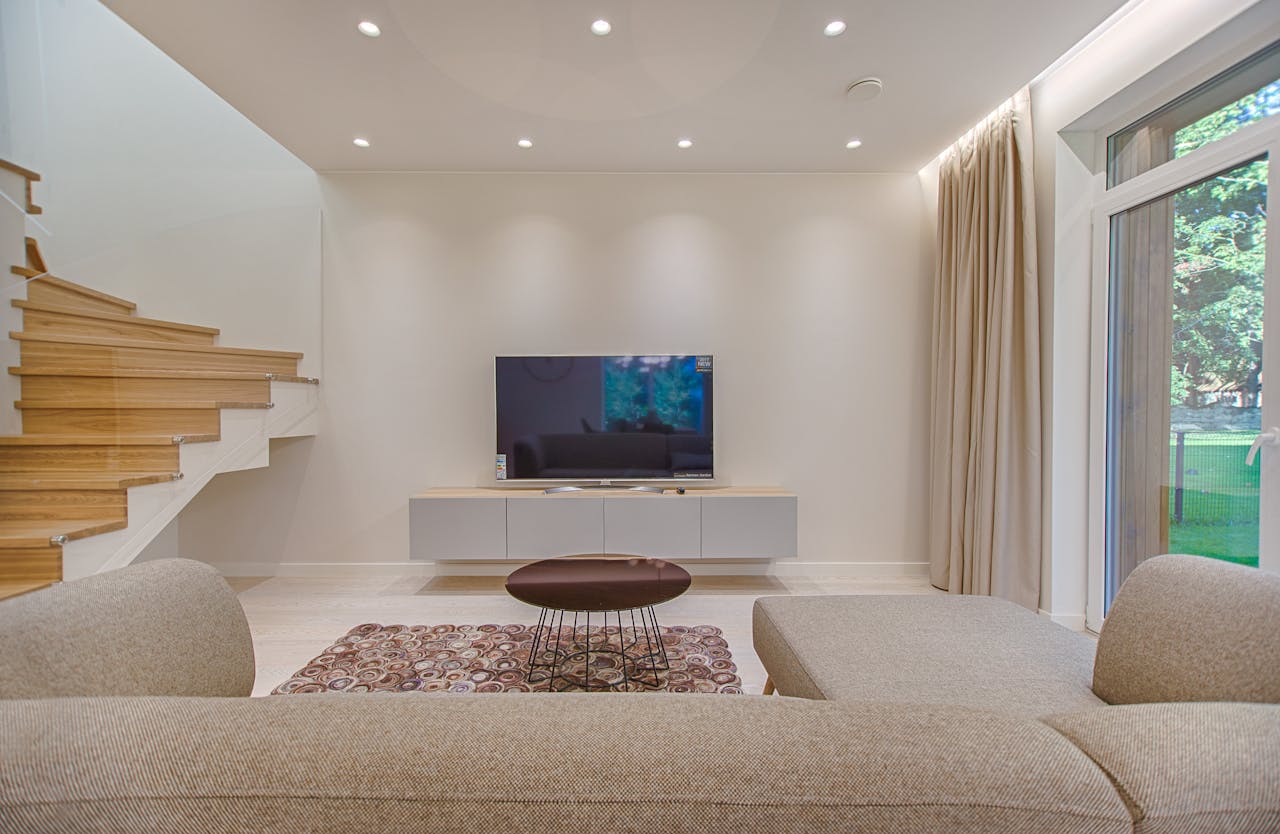our-story Contemporary living room with stylish sofa, TV, and staircase, offering a cozy interior design setting.