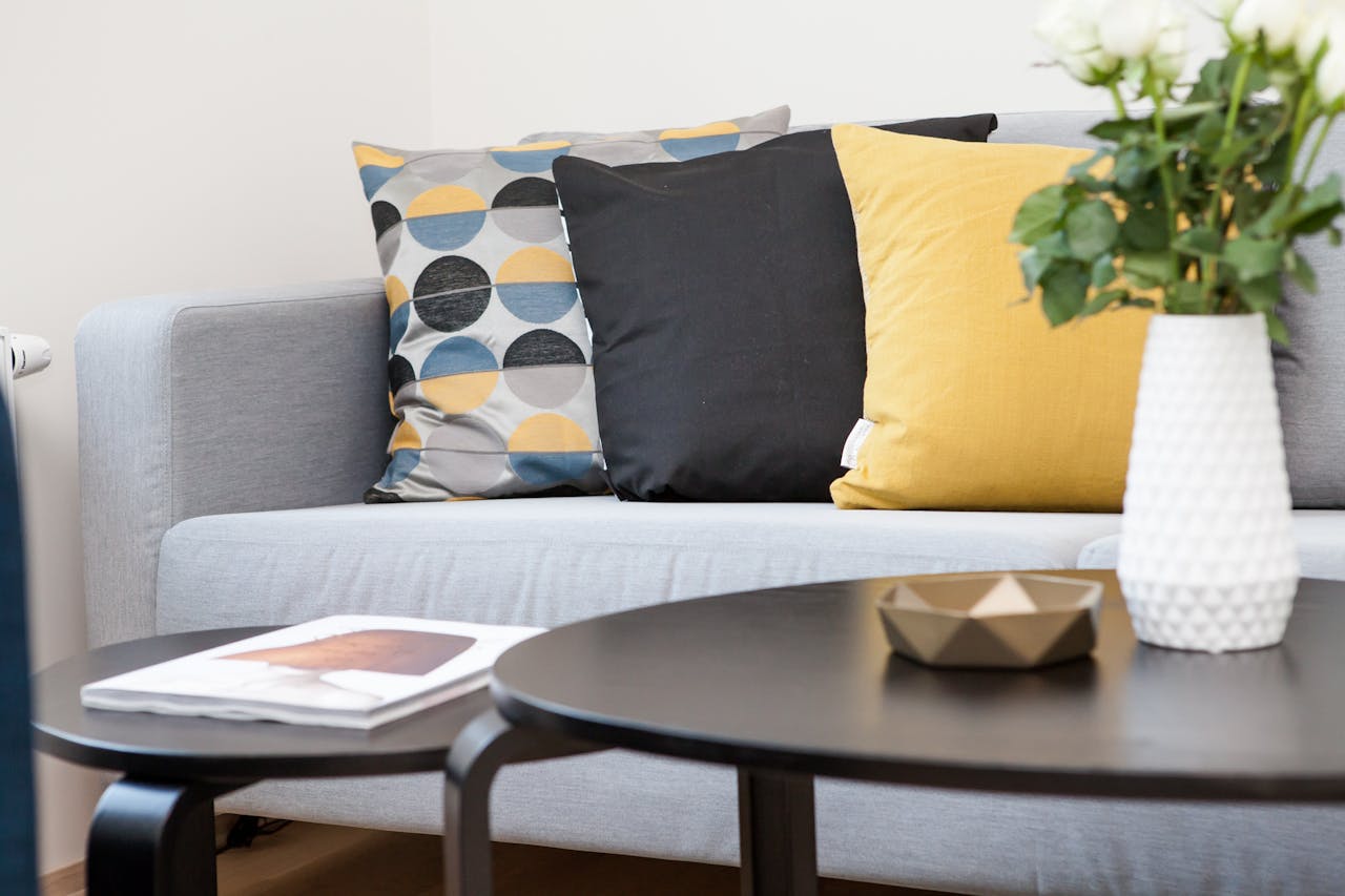 brand-02 Contemporary living room interior featuring a stylish sofa, decorative pillows, and a vase of flowers.